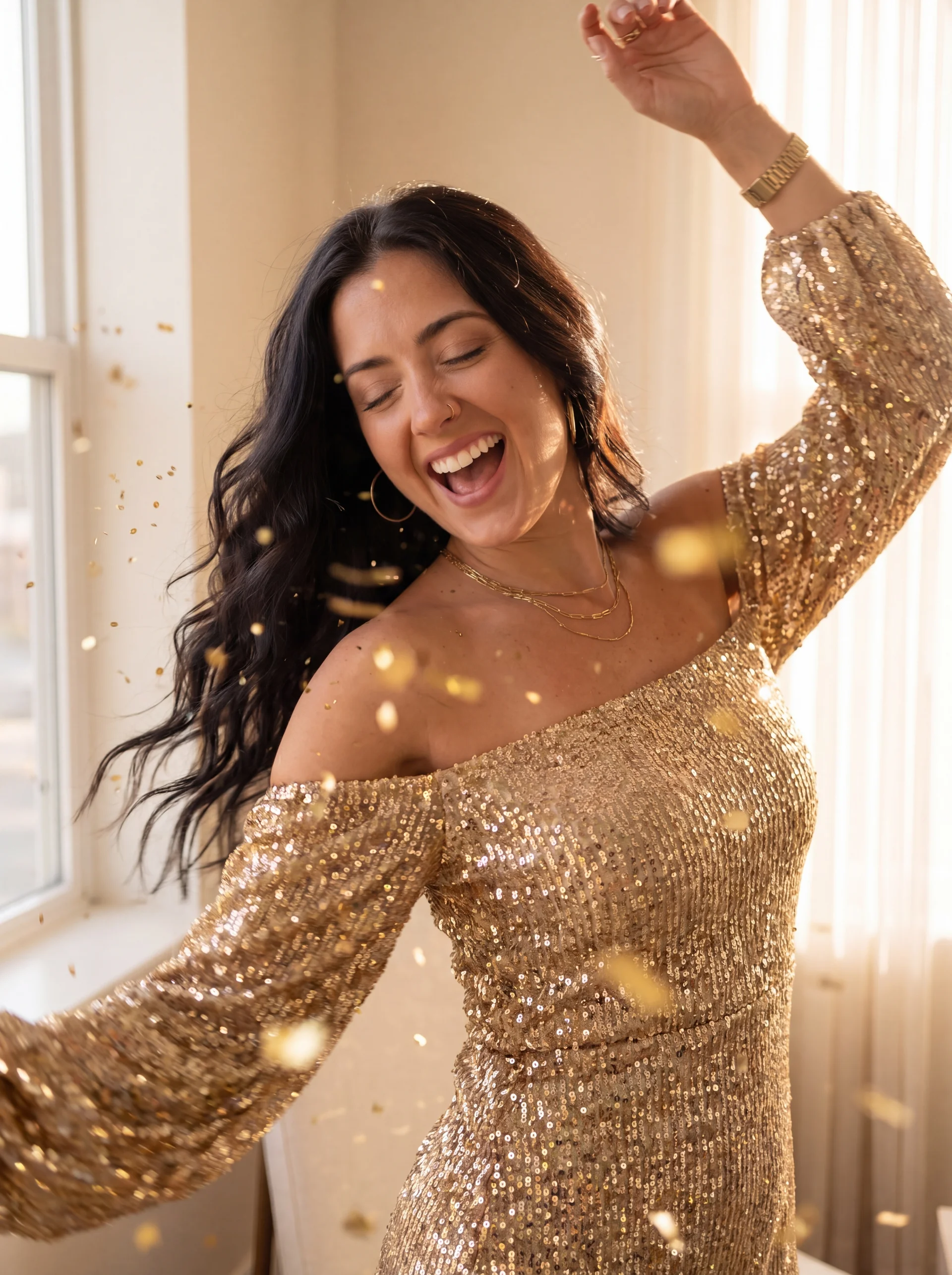 Jac in gold sequin dress dancing with arms raised and gold confetti around her